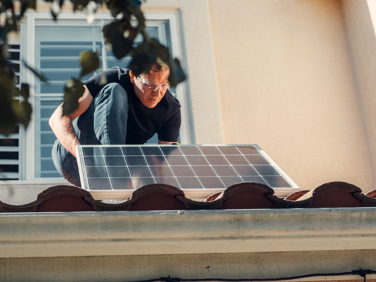 Solar panel technician installing a solar panel on a tile roof in Arizona.