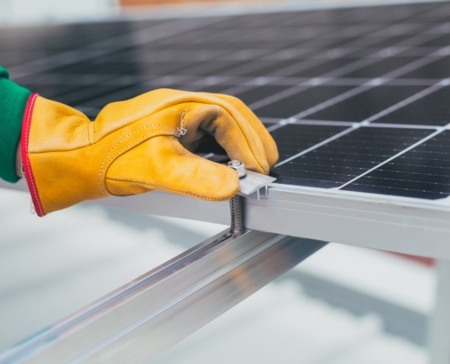 The Importance of Solar Panel Maintenance Gloved hand adjusting bolt on a solar panel.