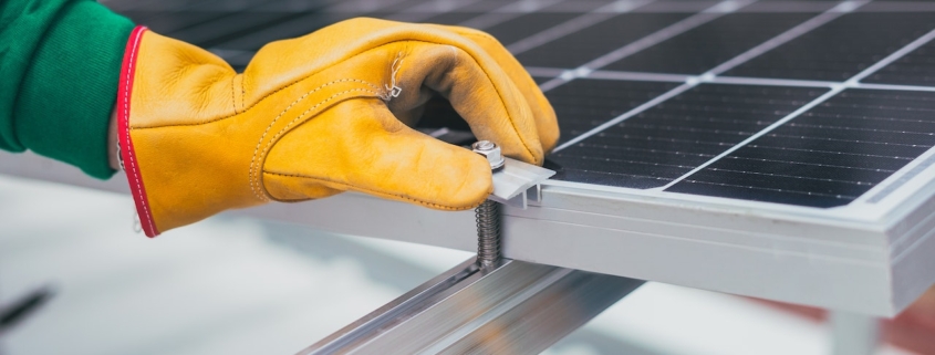 Gloved hand adjusting bolt on a solar panel.